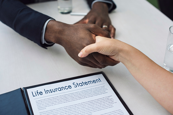 two people shaking hands over a life insurance statement